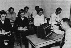 Group of sailors with headphones with an examiner and his equipment in front.