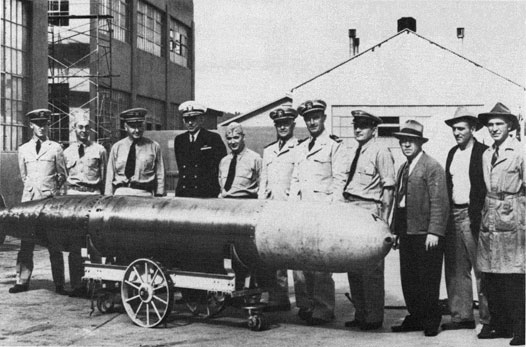 Group of men standing behind a Mk 14 torpedo.
