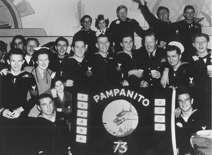 Pampanito's crew gathers around the battle flag at the submarine's decommissioning party, December 15, 1945.