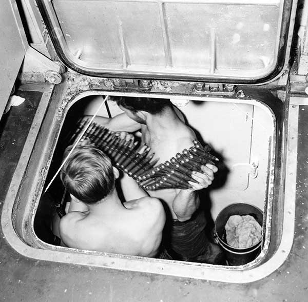 two sailors loading belt of ammo in magazine