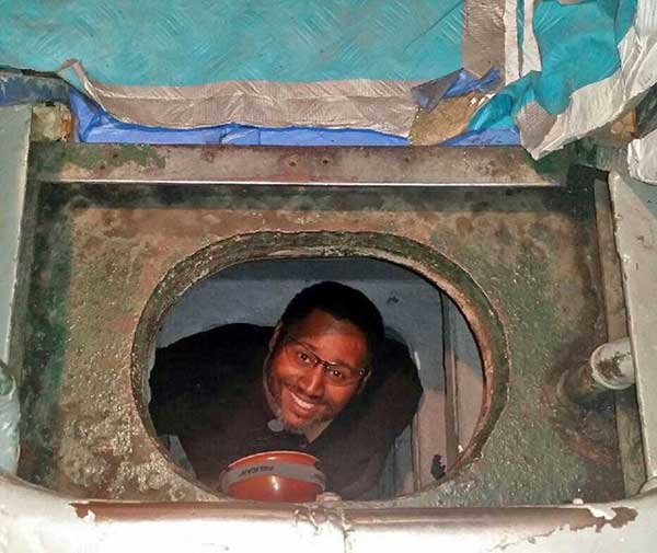Aaron Washington smiling while looking up from inside the sanitary tank