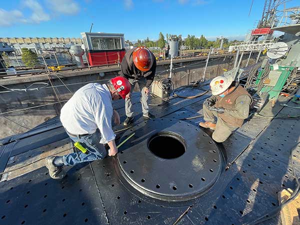 three shipyard crew checking foundation before gun move