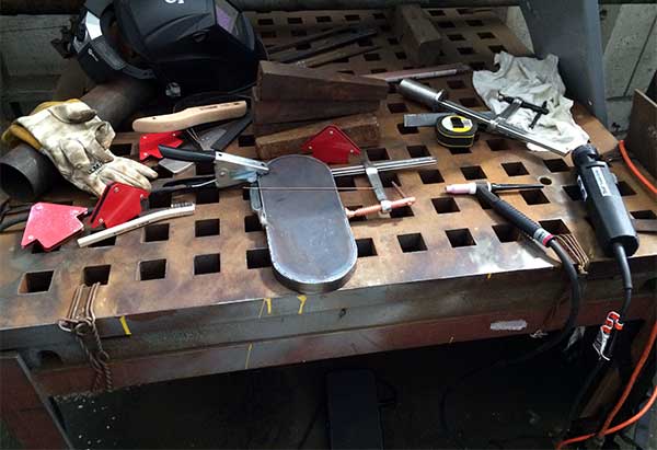 welding table with bofors foot rest after welding with lots of tools scattered about