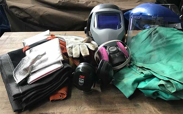 welding hood, fire blankets, gloves, welding goggles, grinding face shield, flange wizard, tig torch on table